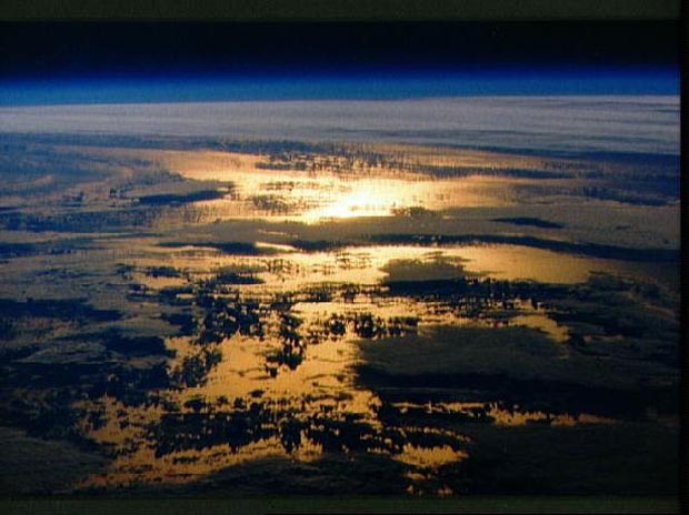 STS-36 Earth Observation of the Sun Beaming off Cloud-covered Ocean Waters